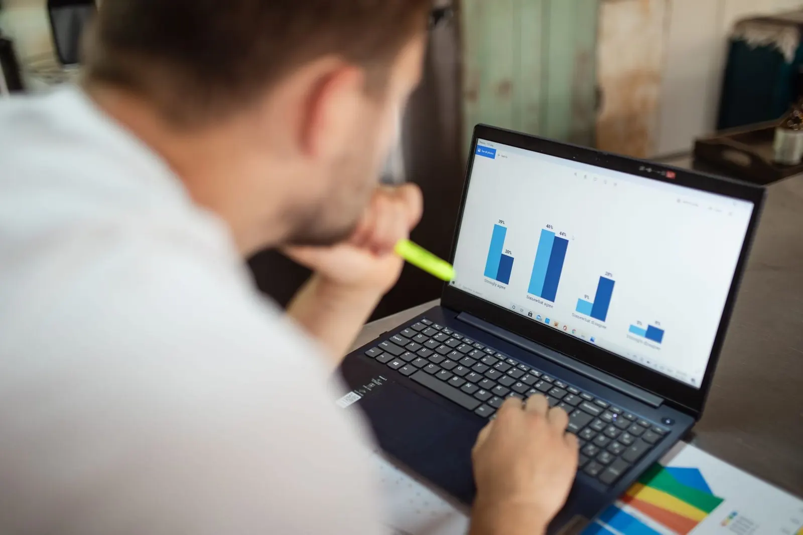 A man reviewing a bar chart on his laptop, seen over his shoulder