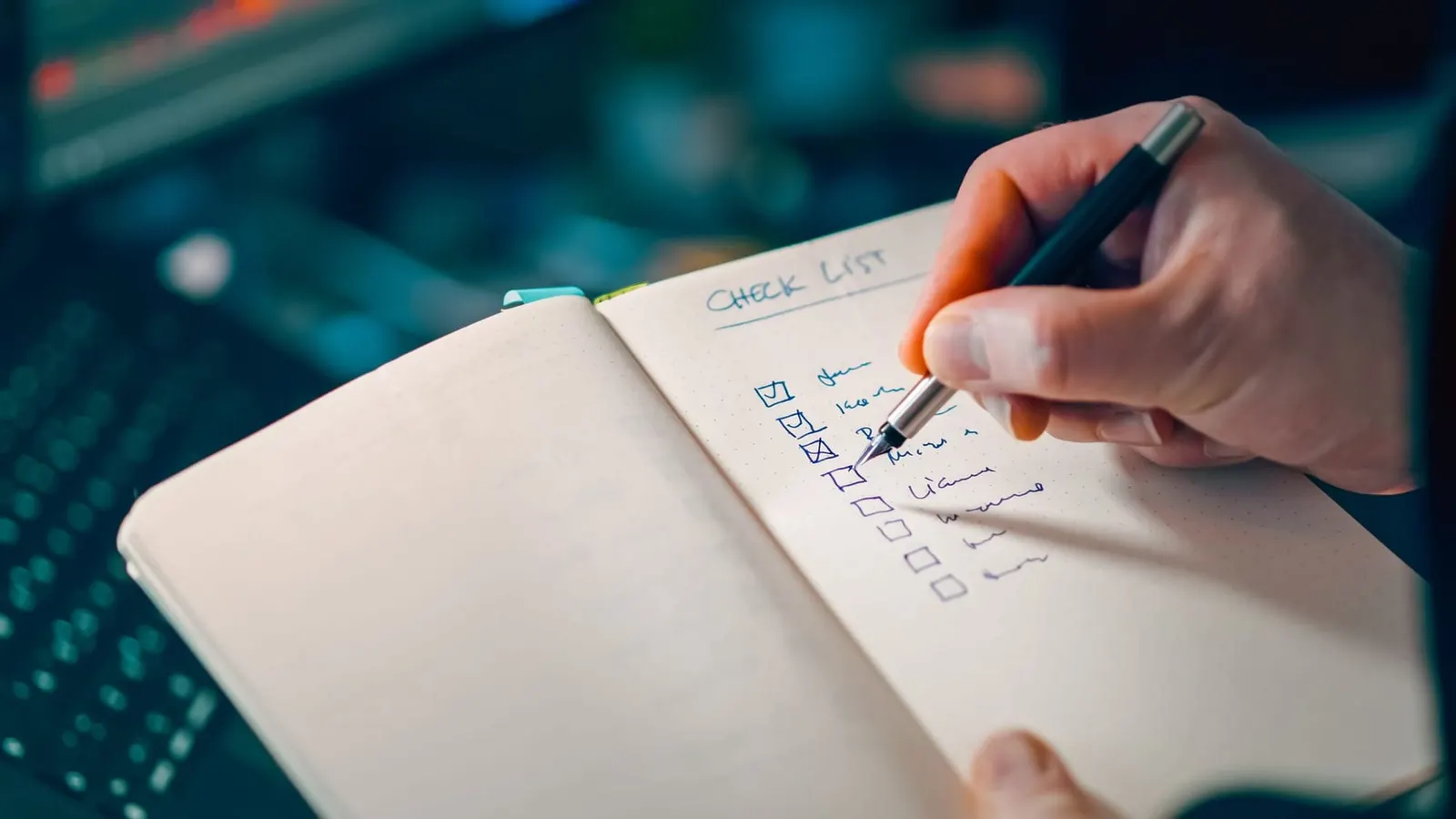 A hand ticking items off a handwritten checklist in a notebook